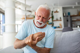 An elderly man experiences discomfort and pain in his fingers and hands. Old man with finger pain, showcasing his actions of massaging his arthritic hand and wrist