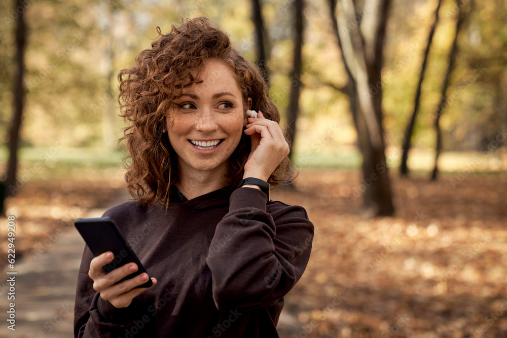 Caucasian woman listening music from mobile phone during the jogging