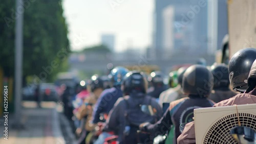  blur image of Jakarta's urban traffic density dominated by motorcycles. Depicts high pollution, heat, and congestion. Taken with a telephoto lens and handheld