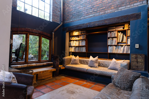 General view of living room with sofas, armchair, bookcase and window