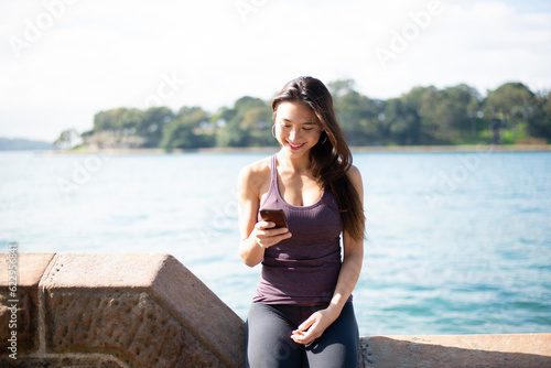 ジム着で水辺でスマホを見ている女性 photo