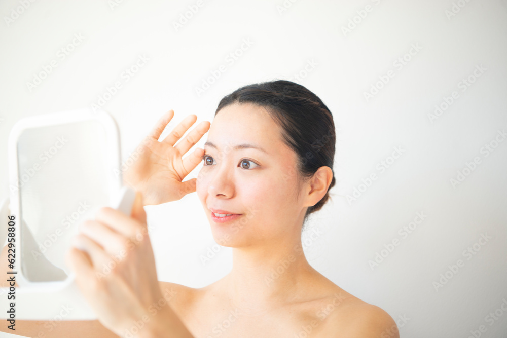 鏡で自分の顔を見ている女性