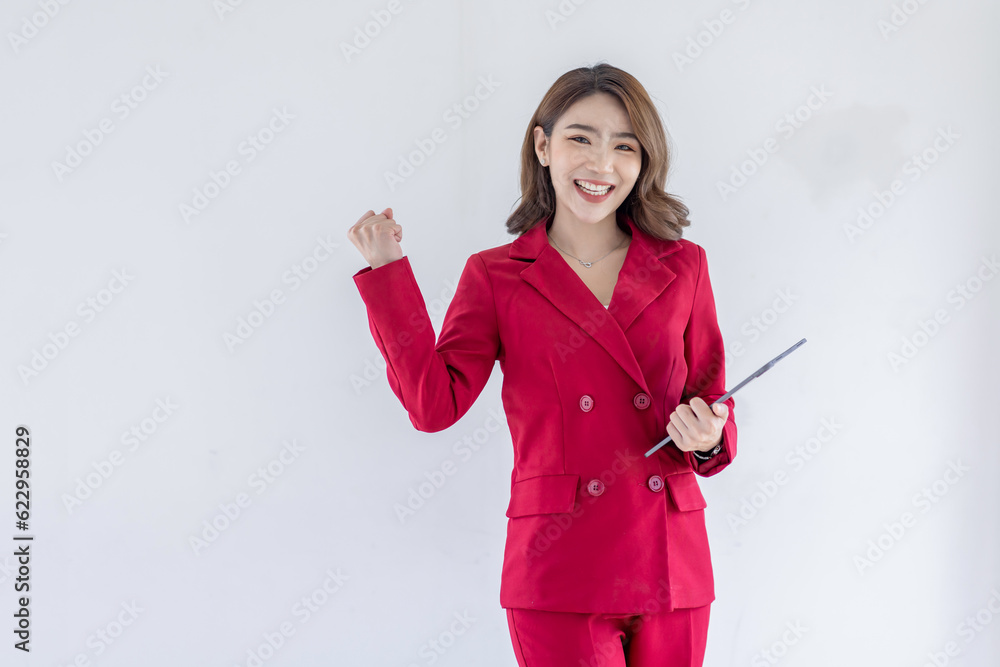 © David - Fun young woman of Asian ethnicity 20s years old wears red suit jacket hold in hand use tablet doing winner gesture clenching fists isolated on plain pastel light white background studio portrait