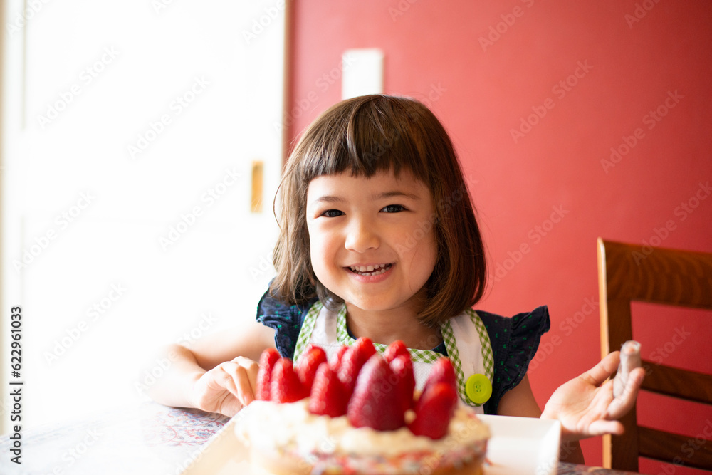 いちごのケーキの前で笑っている女の子