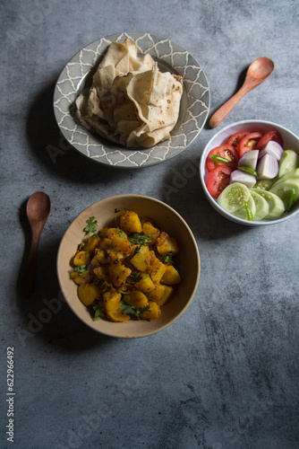 Indian veg lunch rumali roti or Indian bread and alu jeera or potato masala served on a background. Top view, selective focus. photo