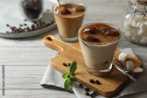 Delicious iced coffee with milk, beans and mint on white wooden table, space for text