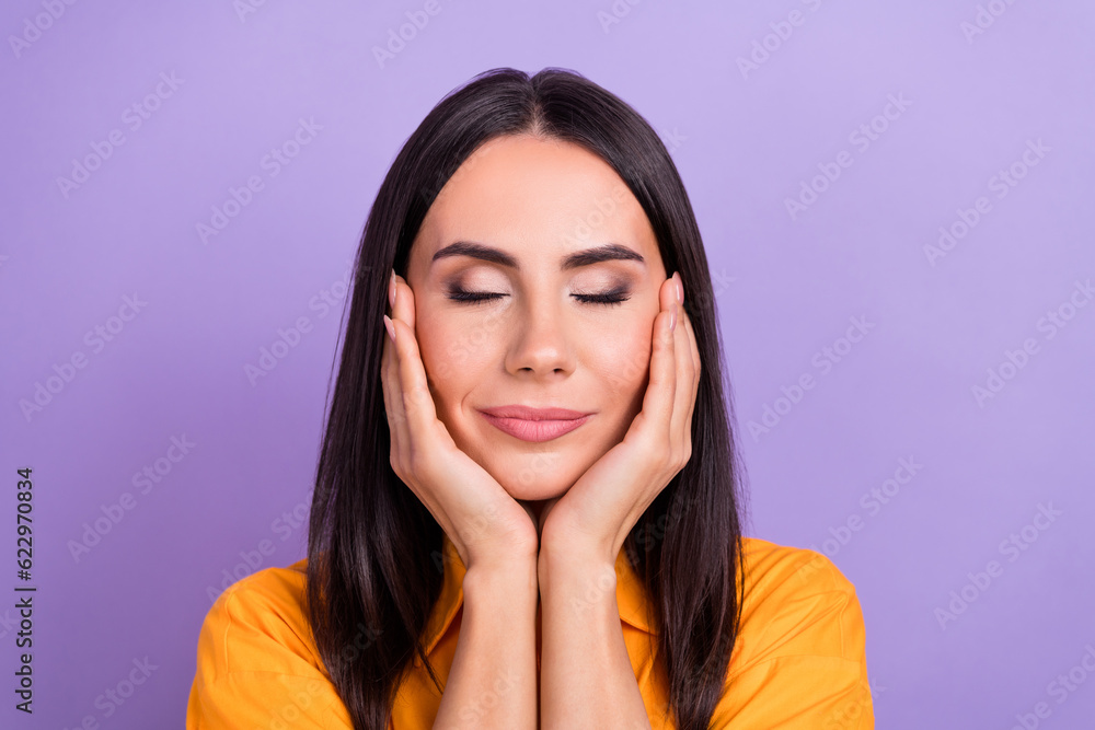 Photo of cheerful peaceful girl with straight hairdo dressed yellow shirt eyes closed hands on cheeks isolated on purple color background Photo of cheerful peaceful girl with straight hairdo dressed yellow shirt eyes closed hands on cheeks isolated on purple color background