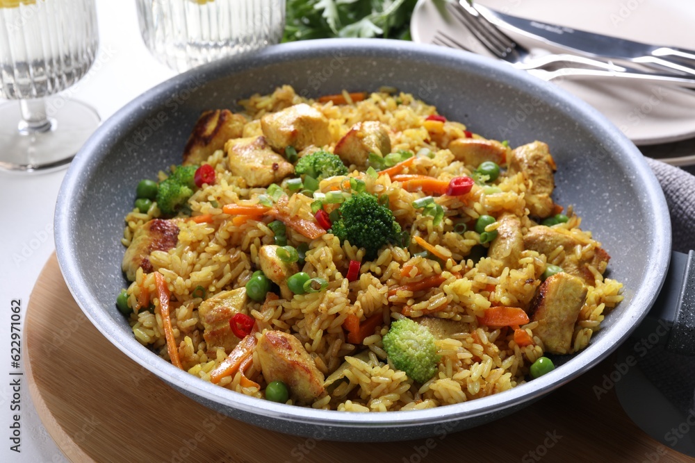 Tasty rice with meat and vegetables in frying pan on white table, closeup Tasty rice with meat and vegetables in frying pan on white table, closeup
