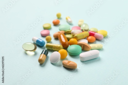 Many different pills on light blue background, closeup