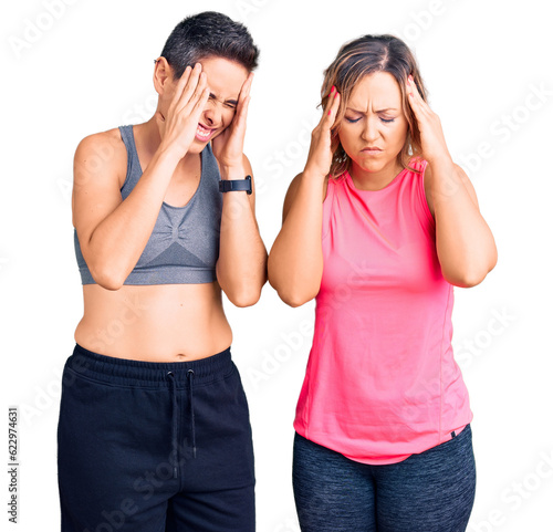 Couple of women wearing sportswear with hand on head, headache because stress. suffering migraine.