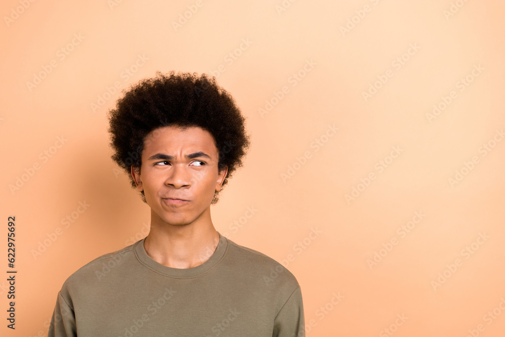 Photo of thoughtful uncertain doubtful guy with afro hairstyle dressed khaki shirt look empty space isolated on beige color background Photo of thoughtful uncertain doubtful guy with afro hairstyle dressed khaki shirt look empty space isolated on beige color background