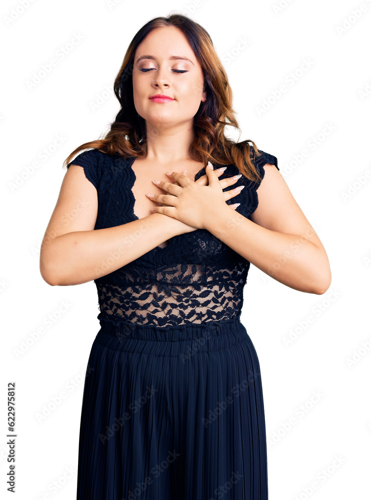 Young beautiful caucasian woman wearing elegant dress smiling with hands on chest with closed eyes and grateful gesture on face. health concept. Young beautiful caucasian woman wearing elegant dress smiling with hands on chest with closed eyes and grateful gesture on face. health concept.