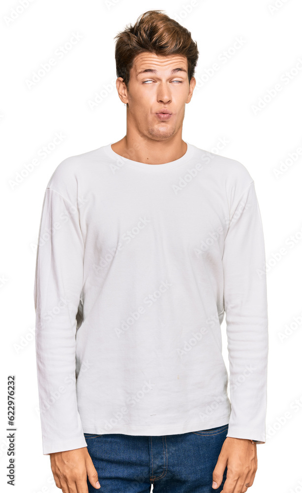 Handsome caucasian man wearing casual white sweater making fish face with lips, crazy and comical gesture. funny expression. Handsome caucasian man wearing casual white sweater making fish face with lips, crazy and comical gesture. funny expression.