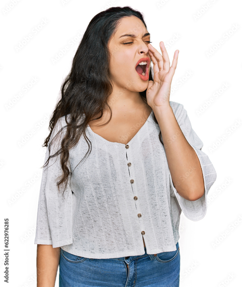 Brunette young woman wearing casual clothes shouting and screaming loud to side with hand on mouth. communication concept. Brunette young woman wearing casual clothes shouting and screaming loud to side with hand on mouth. communication concept.
