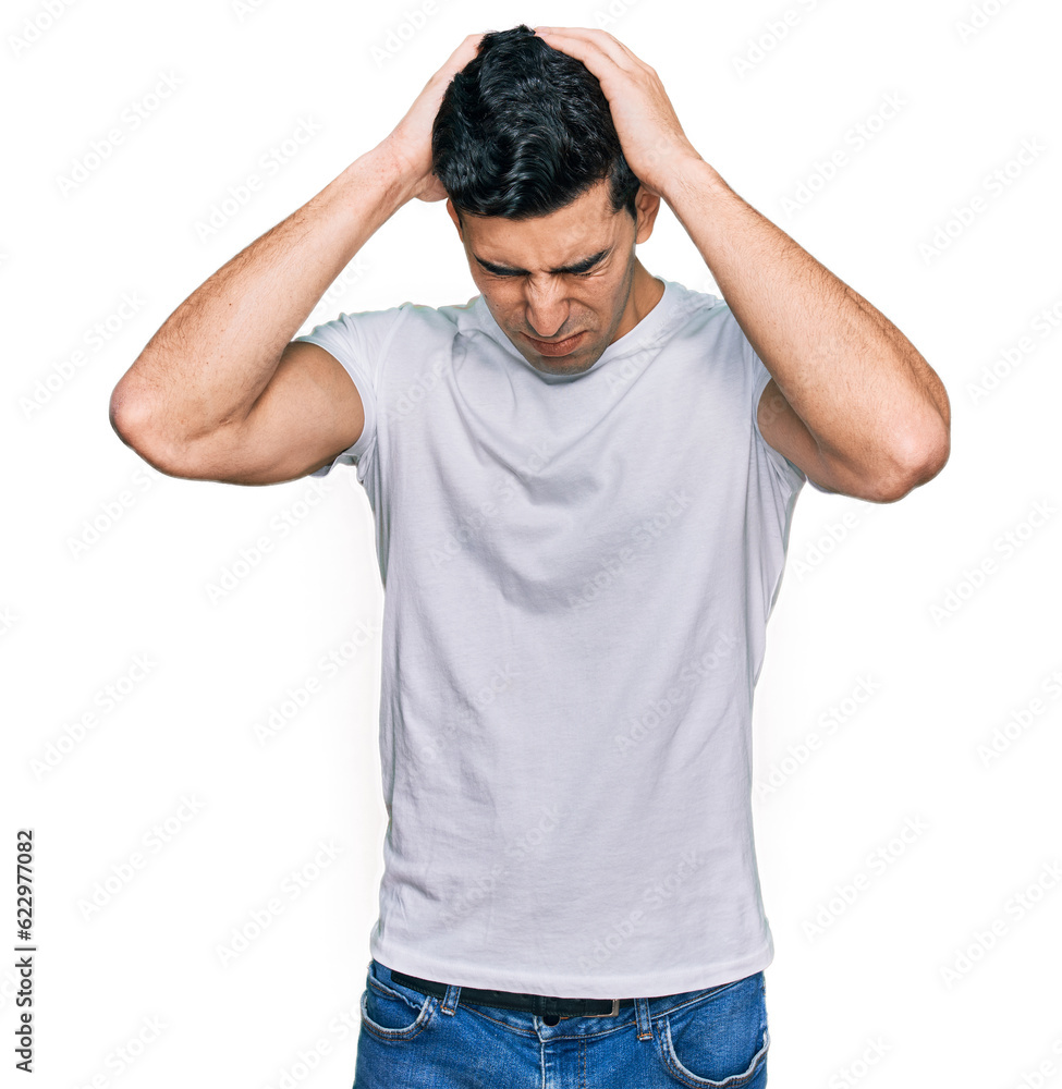 Handsome hispanic man wearing casual white t shirt suffering from headache desperate and stressed because pain and migraine. hands on head. Handsome hispanic man wearing casual white t shirt suffering from headache desperate and stressed because pain and migraine. hands on head.