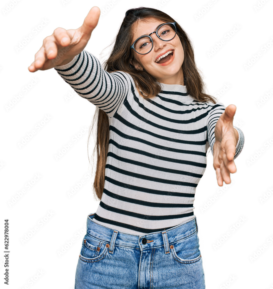 Young beautiful teen girl wearing casual clothes and glasses looking at the camera smiling with open arms for hug. cheerful expression embracing happiness. Young beautiful teen girl wearing casual clothes and glasses looking at the camera smiling with open arms for hug. cheerful expression embracing happiness.