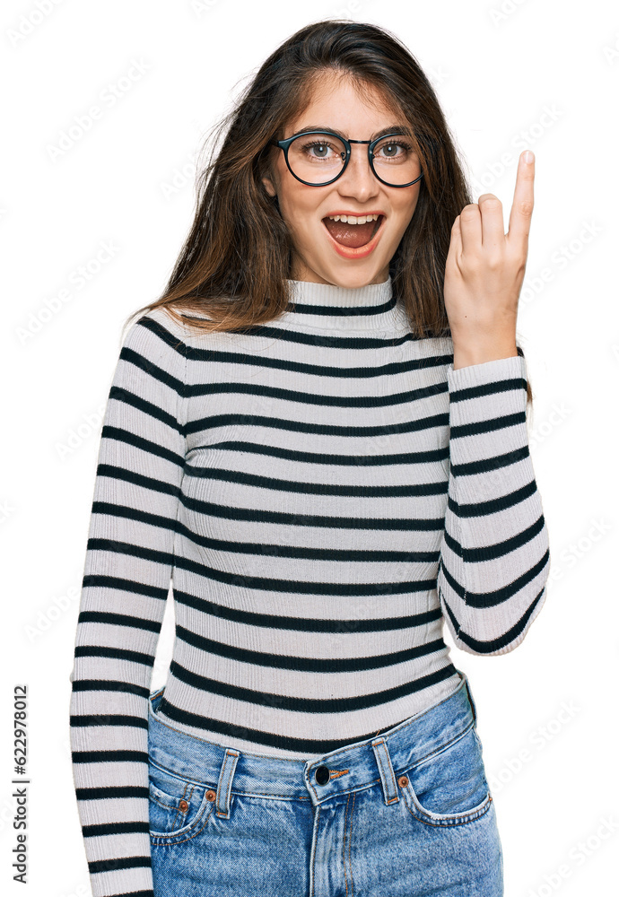 Young beautiful teen girl wearing casual clothes and glasses pointing finger up with successful idea. exited and happy. number one.