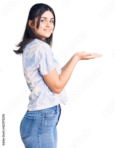 Young beautiful girl wearing casual t shirt pointing aside with hands open palms showing copy space, presenting advertisement smiling excited happy