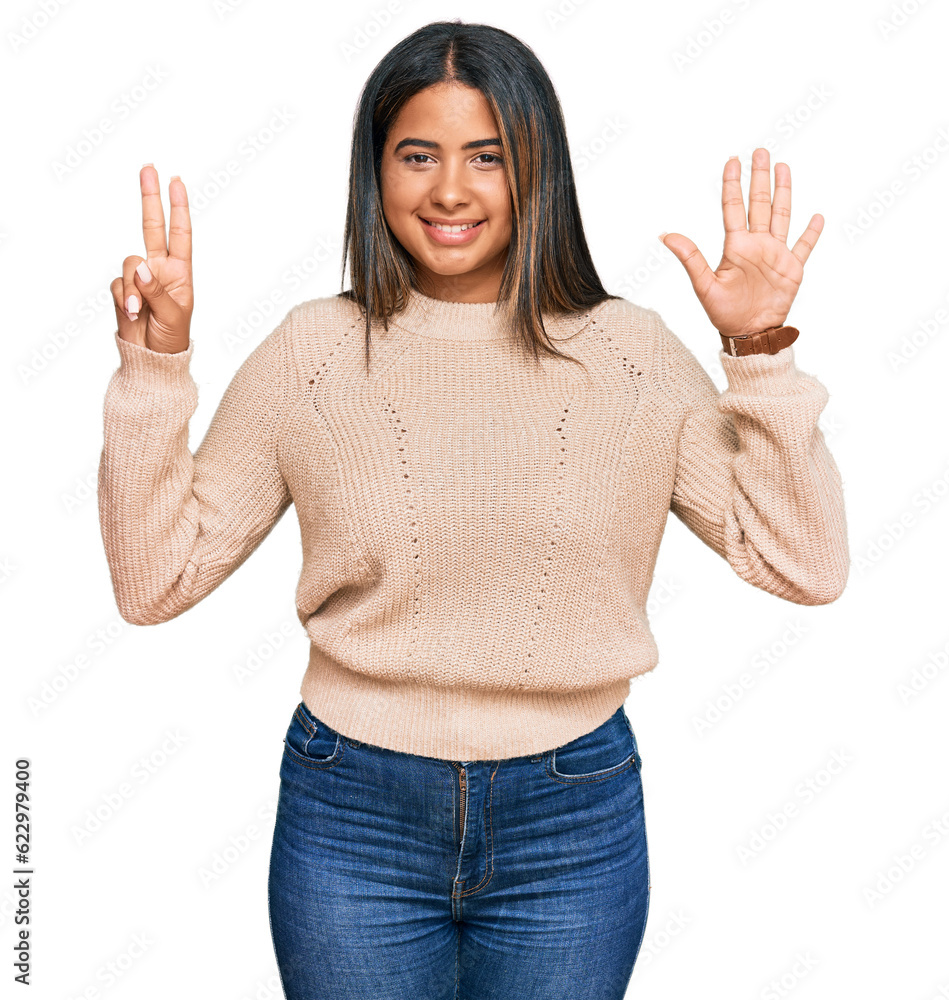 Young latin girl wearing wool winter sweater showing and pointing up with fingers number seven while smiling confident and happy. Young latin girl wearing wool winter sweater showing and pointing up with fingers number seven while smiling confident and happy.