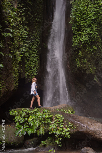 Travel lifestyle. Young traveler woman at waterfall in tropical forest. Leke Leke waterfall, Bali, Indonesia