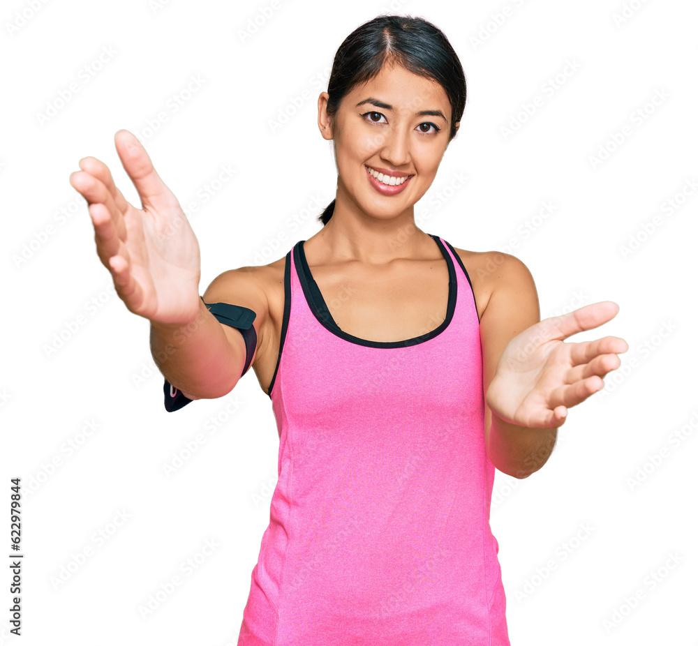 Beautiful asian young sport woman wearing sportswear and arm band looking at the camera smiling with open arms for hug. cheerful expression embracing happiness. Beautiful asian young sport woman wearing sportswear and arm band looking at the camera smiling with open arms for hug. cheerful expression embracing happiness.