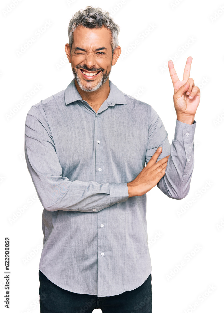 Middle age grey-haired man wearing casual clothes smiling with happy face winking at the camera doing victory sign. number two.