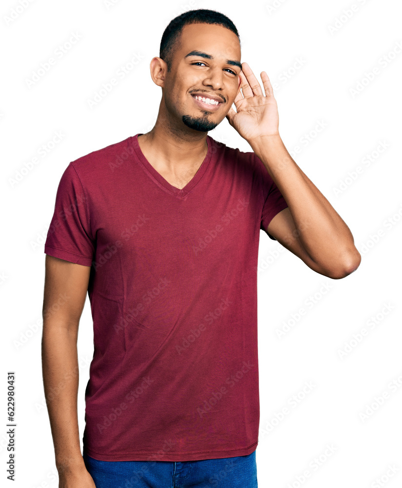 Young african american man wearing casual t shirt smiling with hand over ear listening and hearing to rumor or gossip. deafness concept. Young african american man wearing casual t shirt smiling with hand over ear listening and hearing to rumor or gossip. deafness concept.