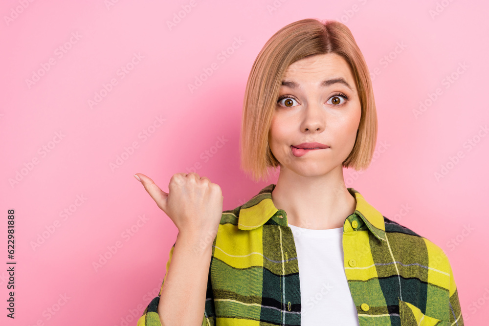 Photo portrait of lovely young lady point empty space nervous dressed stylish checkered yellow look isolated on pink color background Photo portrait of lovely young lady point empty space nervous dressed stylish checkered yellow look isolated on pink color background