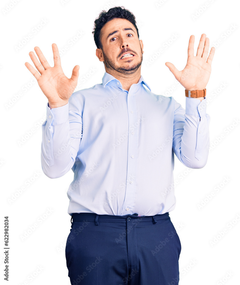 Young hispanic man wearing business clothes afraid and terrified with fear expression stop gesture with hands, shouting in shock. panic concept. Young hispanic man wearing business clothes afraid and terrified with fear expression stop gesture with hands, shouting in shock. panic concept.