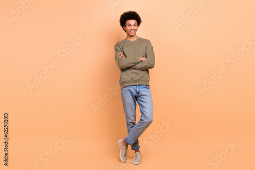 Full size photo of positive cheerful good mood guy with afro hairstyle wear khaki shirt arms crossed isolated on beige color background © deagreez