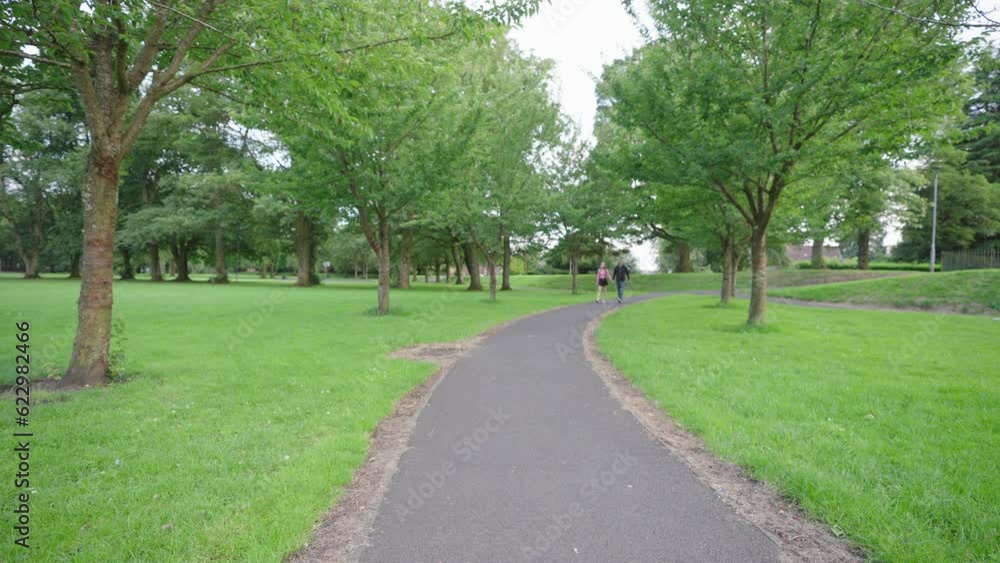 Dad and daughter holding hands and walking along a path between trees Dad and daughter holding hands and walking along a path between trees