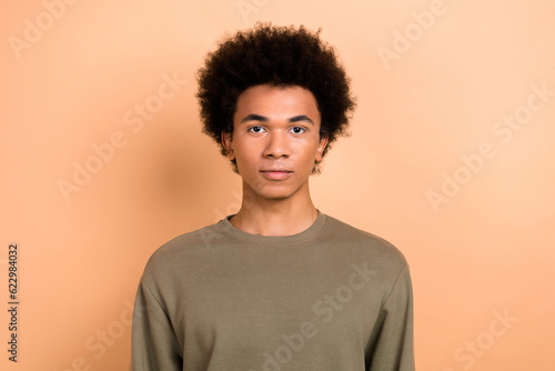 Photo of handsome nice optimistic young positive guy with afro hairstyle dressed khaki shirt staring isolated on beige color background © deagreez