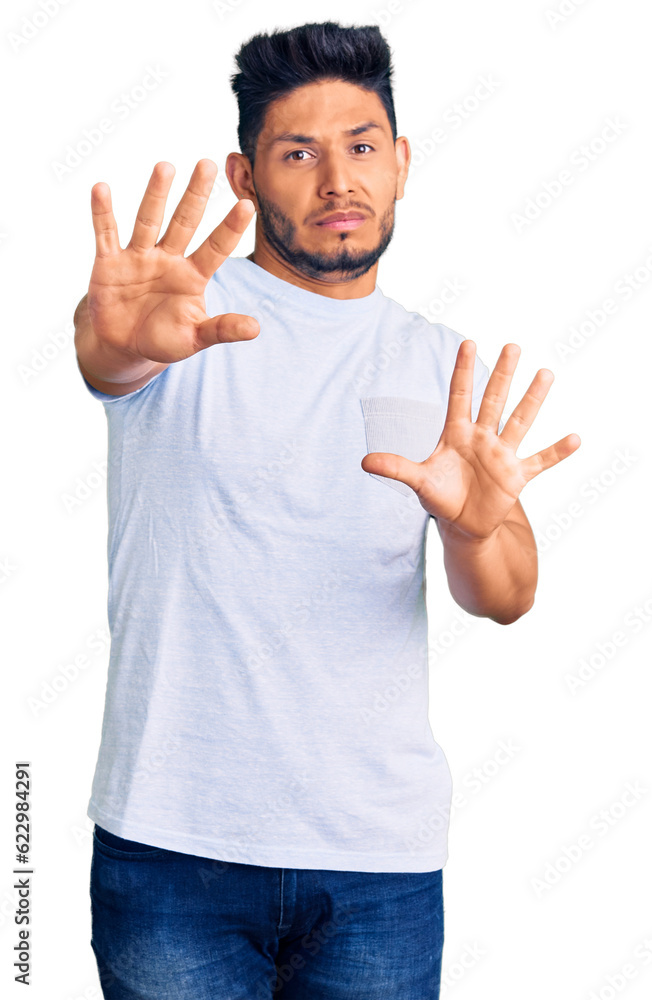 Handsome latin american young man wearing casual clothes afraid and terrified with fear expression stop gesture with hands, shouting in shock. panic concept. Handsome latin american young man wearing casual clothes afraid and terrified with fear expression stop gesture with hands, shouting in shock. panic concept.