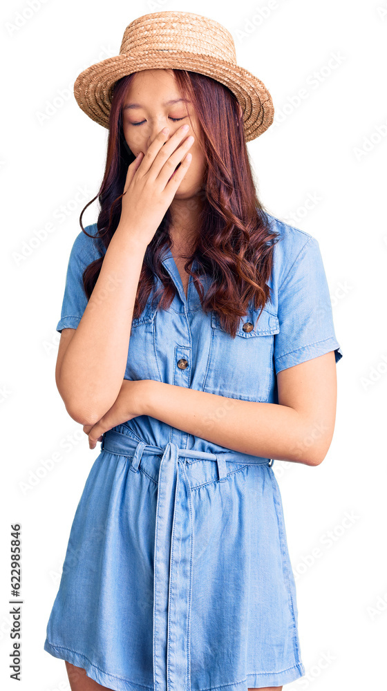 Young beautiful chinese girl wearing summer hat bored yawning tired covering mouth with hand. restless and sleepiness. Young beautiful chinese girl wearing summer hat bored yawning tired covering mouth with hand. restless and sleepiness.