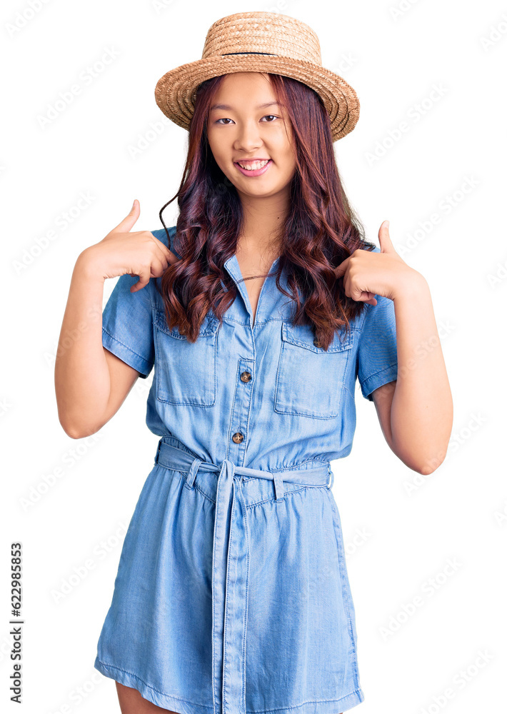 Young beautiful chinese girl wearing summer hat looking confident with smile on face, pointing oneself with fingers proud and happy. Young beautiful chinese girl wearing summer hat looking confident with smile on face, pointing oneself with fingers proud and happy.