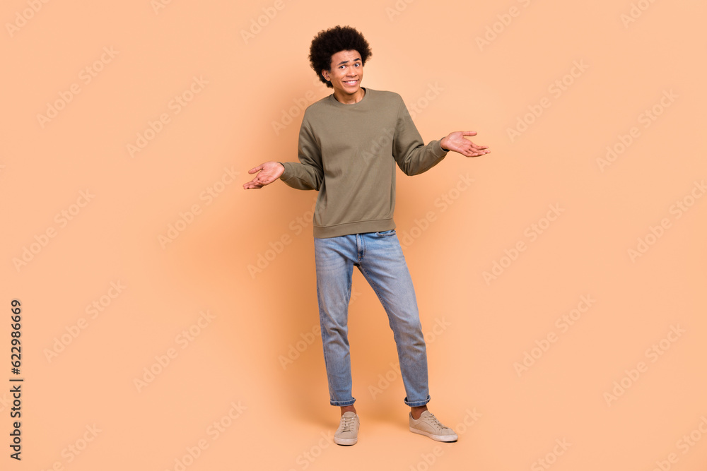 Full body length photo of excited unsure funny guy shrug shoulders no idea misunderstanding dont know answer isolated on beige color background Full body length photo of excited unsure funny guy shrug shoulders no idea misunderstanding dont know answer isolated on beige color background