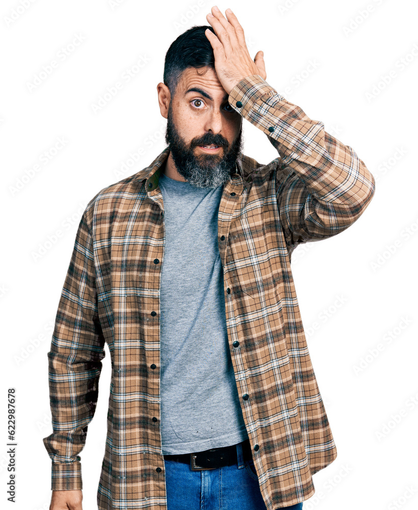 Hispanic man with beard wearing casual shirt surprised with hand on head for mistake, remember error. forgot, bad memory concept. Hispanic man with beard wearing casual shirt surprised with hand on head for mistake, remember error. forgot, bad memory concept.
