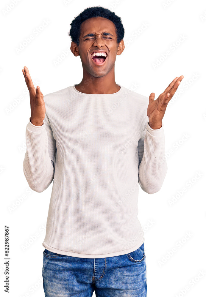 Fototapeta premium African handsome man wearing casual winter sweater celebrating mad and crazy for success with arms raised and closed eyes screaming excited. winner concept