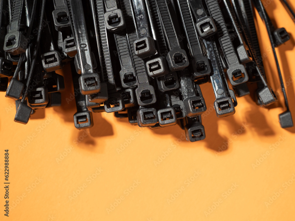 Plastic black ties on an orange background. Plastic ties for cables. Plastic black ties on an orange background. Plastic ties for cables.