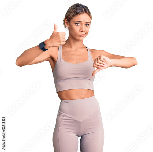 Beautiful caucasian woman wearing sportswear doing thumbs up and down, disagreement and agreement expression. crazy conflict