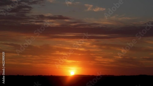 Quick Time Lapse of the Beautiful Golden Sunset in the Field. The Sun Sets Over The Horizon In A Colorful Orange Blue Sky With Clouds. Dramatic Sunset. Incredible Colored Sky Sun and Clouds at Sunset. photo