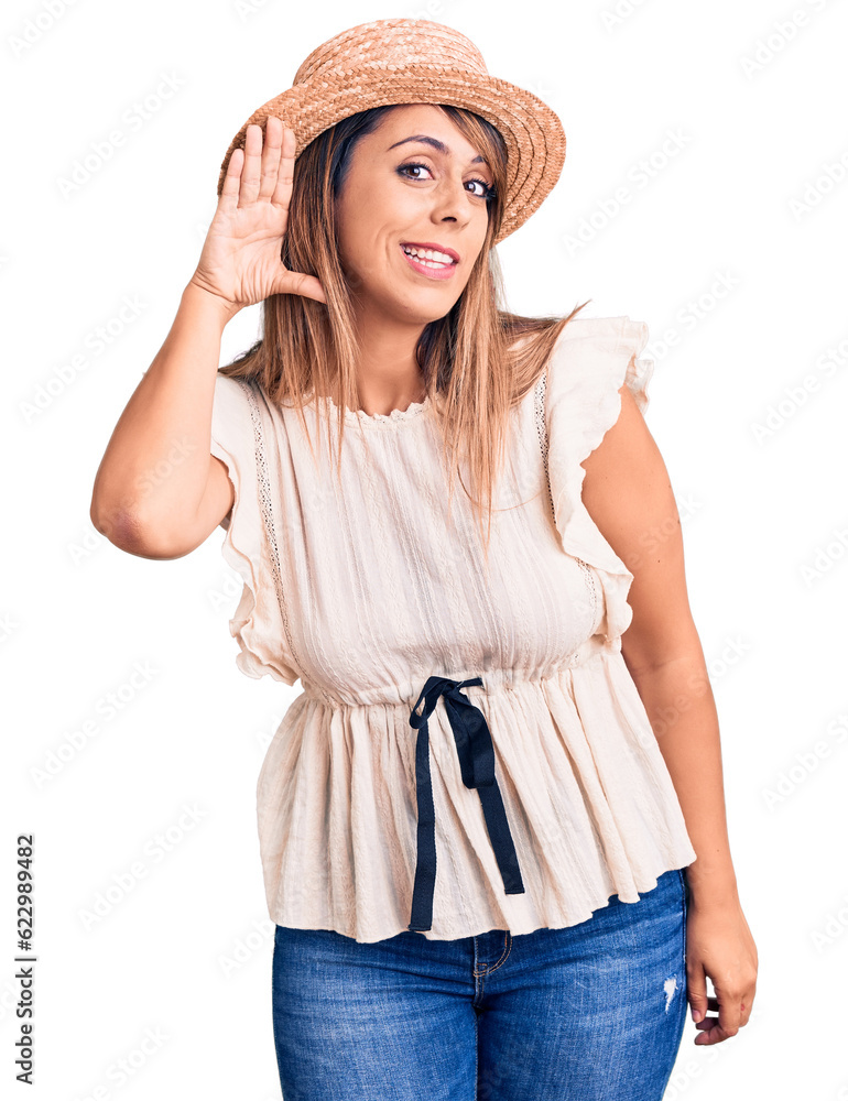 Young beautiful woman wearing summer hat and t-shirt smiling with hand over ear listening an hearing to rumor or gossip. deafness concept. Young beautiful woman wearing summer hat and t-shirt smiling with hand over ear listening an hearing to rumor or gossip. deafness concept.
