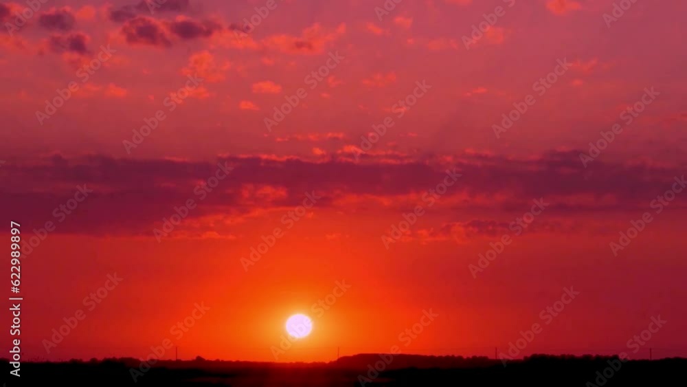 Bright Red Orange Sky at Sunset Clouds, Sun Sets Over Horizon in Time Lapse Field. Colorful Sunset Sky Sun and Clouds. Background 4K. Bright Red Orange Sky at Sunset Clouds, Sun Sets Over Horizon in Time Lapse Field. Colorful Sunset Sky Sun and Clouds. Background 4K.