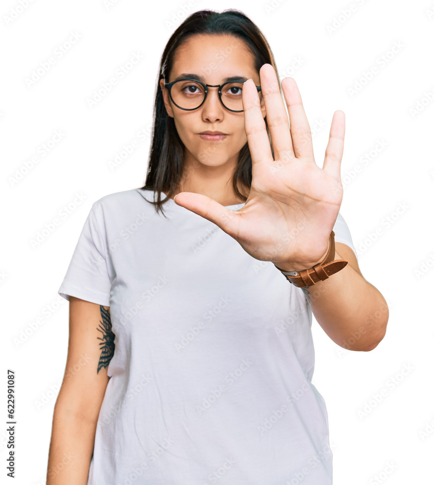 Young hispanic woman wearing casual white t shirt doing stop sing with palm of the hand. warning expression with negative and serious gesture on the face. Young hispanic woman wearing casual white t shirt doing stop sing with palm of the hand. warning expression with negative and serious gesture on the face.