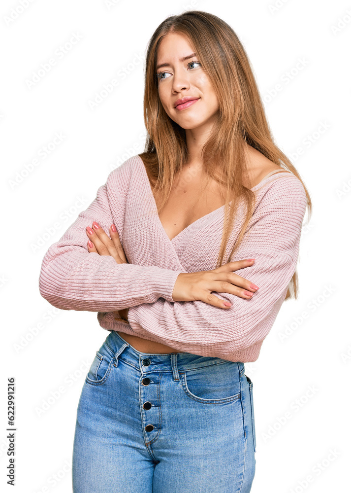 Beautiful blonde woman wearing casual winter pink sweater looking to the side with arms crossed convinced and confident Beautiful blonde woman wearing casual winter pink sweater looking to the side with arms crossed convinced and confident