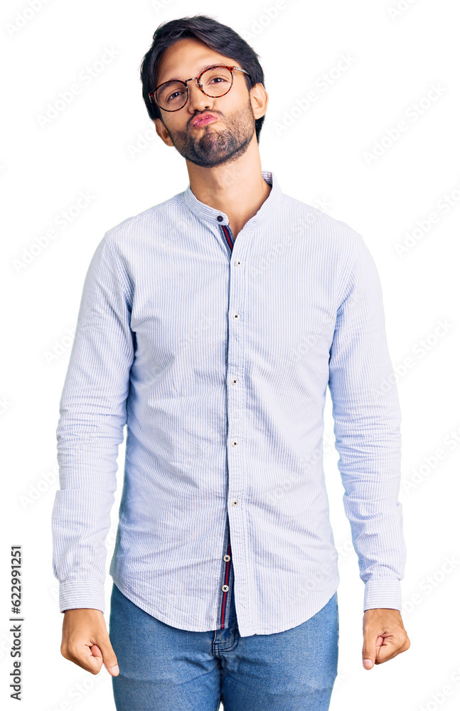 Fototapeta premium Handsome hispanic man wearing business shirt and glasses looking at the camera blowing a kiss on air being lovely and sexy. love expression.