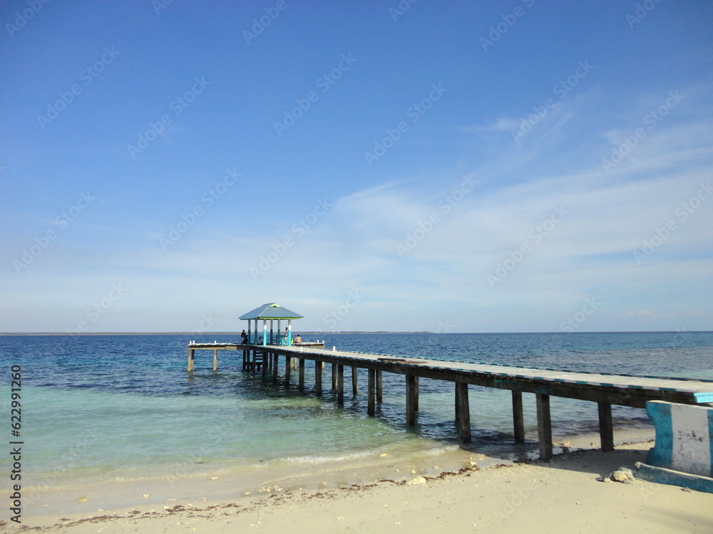 A Pier at Beautiful White Sand Beach Located in North Maluku, Indonesia. Beautiful Scenery of Blue Sky, Ocean and White Sand Beach.