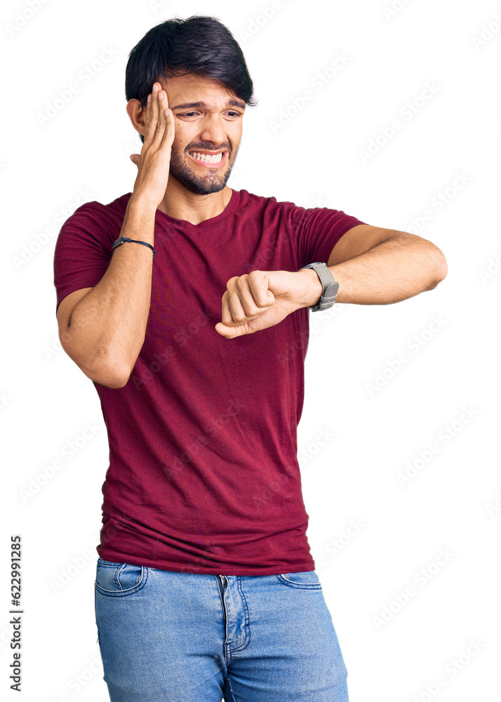 Handsome hispanic man wearing casual clothes looking at the watch time worried, afraid of getting late Handsome hispanic man wearing casual clothes looking at the watch time worried, afraid of getting late