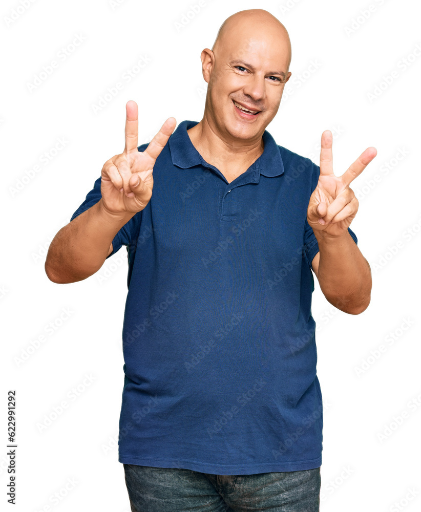 Middle age bald man wearing casual clothes smiling looking to the camera showing fingers doing victory sign. number two. Middle age bald man wearing casual clothes smiling looking to the camera showing fingers doing victory sign. number two.