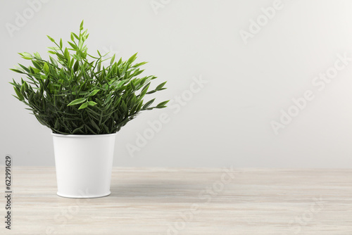 Fototapeta Naklejka Na Ścianę i Meble -  Beautiful artificial plant in flower pot on wooden table against light grey background, space for text